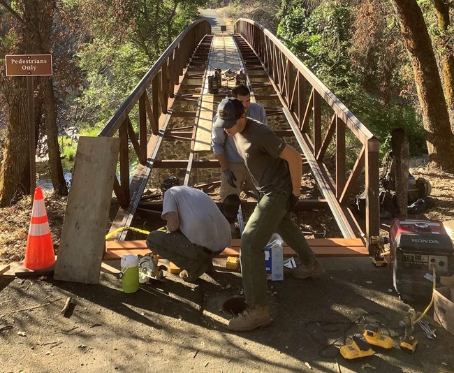 Park employees rebuilding the footbridge across Clear Creek within the Tower House Historic District. The bridge burned during the Carr Fire of 2018.