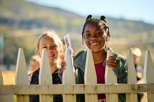 All smiles during the field trip! These two girls stand in the Camden House front yard during the Wintu of Whiskeytown field trip program.