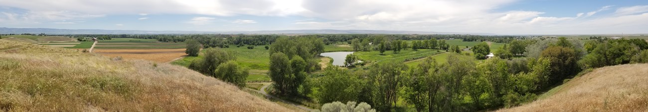 panoramic view from a hill looking out over fields and mountains in the distance
