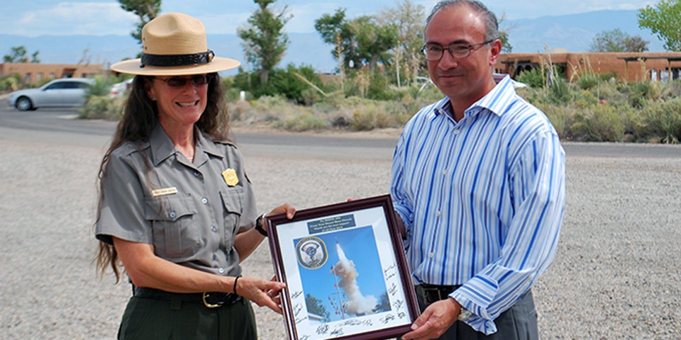 Two individuals holding an image of a rocket launching into the sky.
