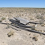 Old boards or pieces of a structure lying in arid scrub grassland