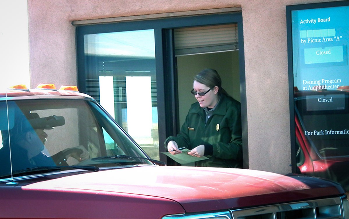Park ranger speaking to park visitor at entrance booth.
