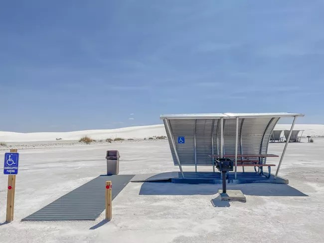 A large accessible picnic table in white sand