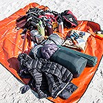 A pile of gear and hiking supplies spread on an orange tarp