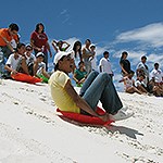 A group of youth sledding on white dunes