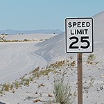 White 25 mph  speed limit sign along a sand road