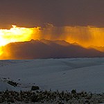 Sunset with rain showers and white dunes in the foreground