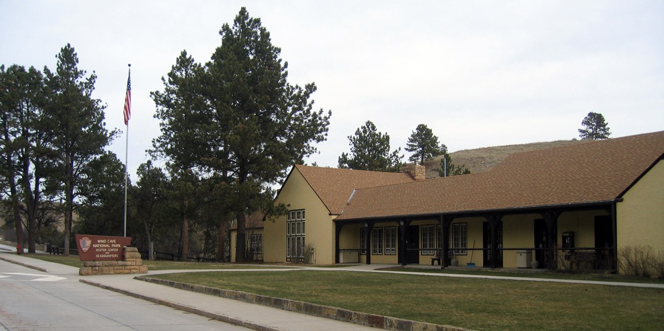 a large yellow building with a brown roof, trim, and a wide green lawn with a concrete driveway