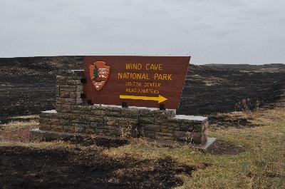 Wind Cave National Park headquarters sign with burned black prairie around it
