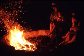 Visitors sit by an evening campfire.