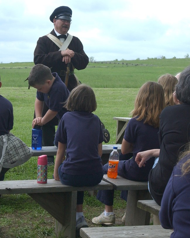 A living historian in 19th century military dress talking to a group of students and parents.