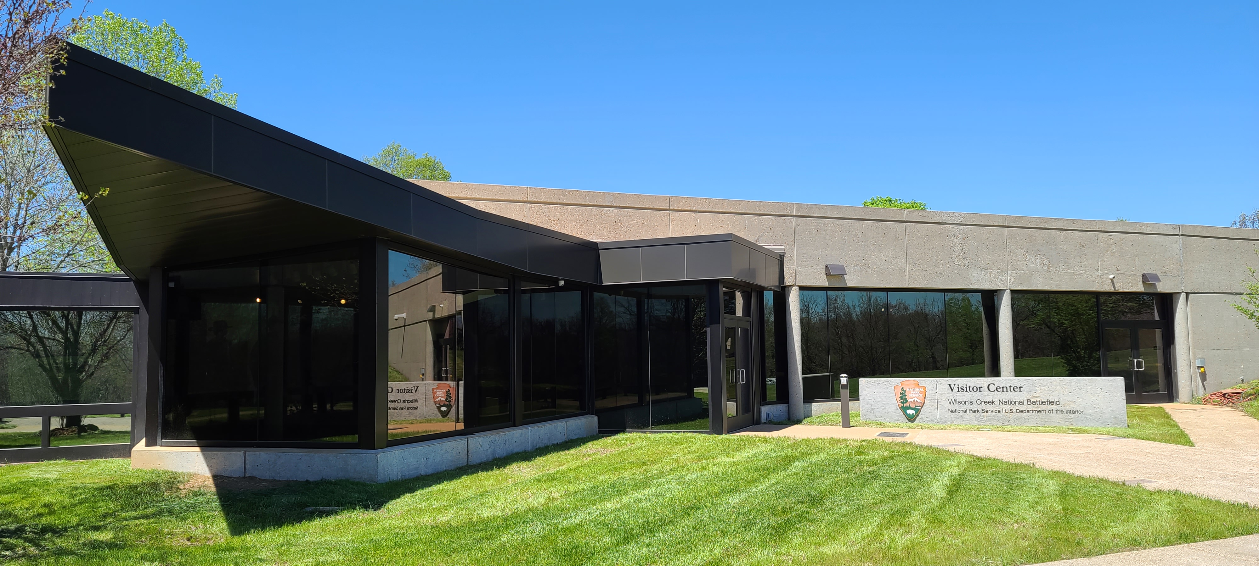 Front of Visitor Center Building with Arrowhead on sign reading "Wilson's Creek National Battlefield, National Park Service, US Department of the Interior