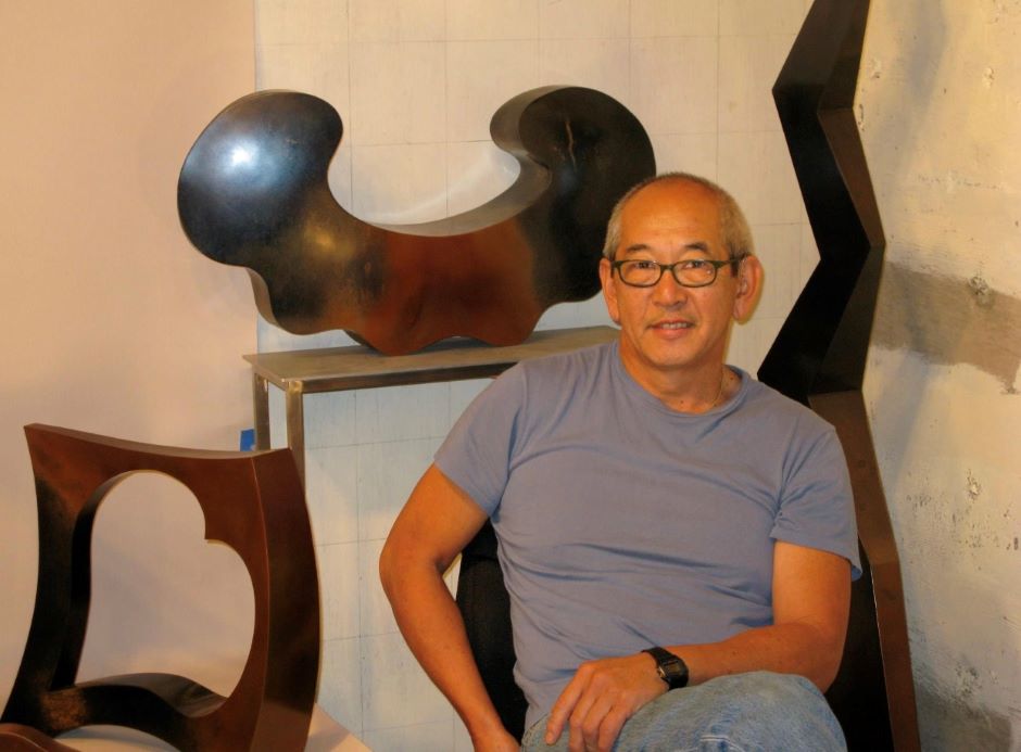 The artist seated in front of a few of his smaller works