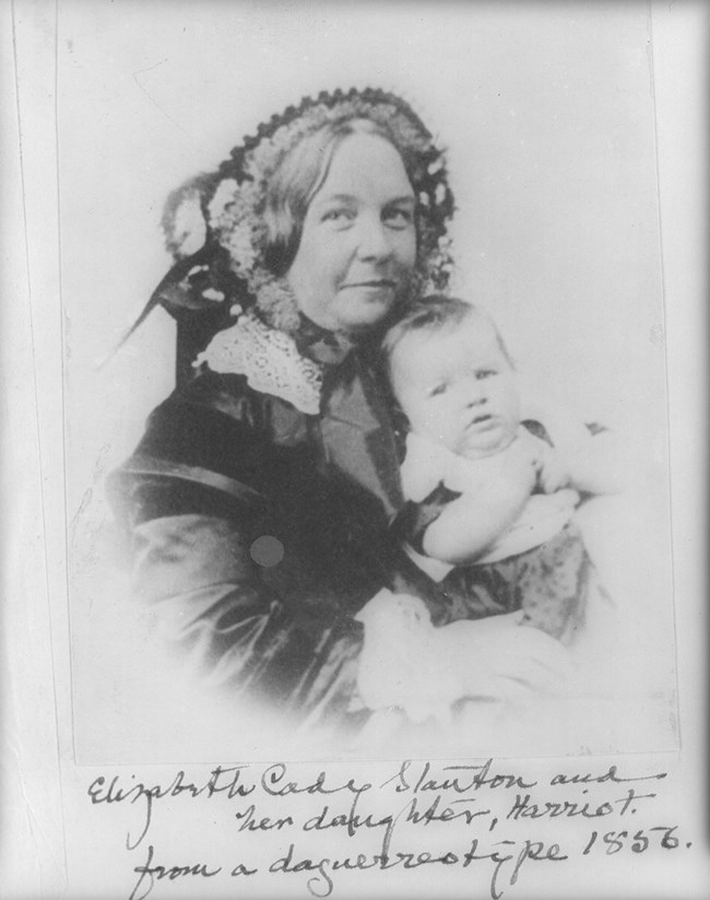 A woman in a bonnet holding a small baby.