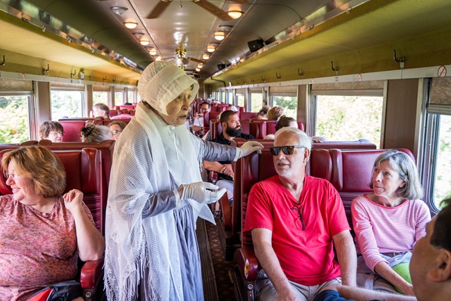 A living historian portraying Lucretia Mott speaks to visitors on a train car.