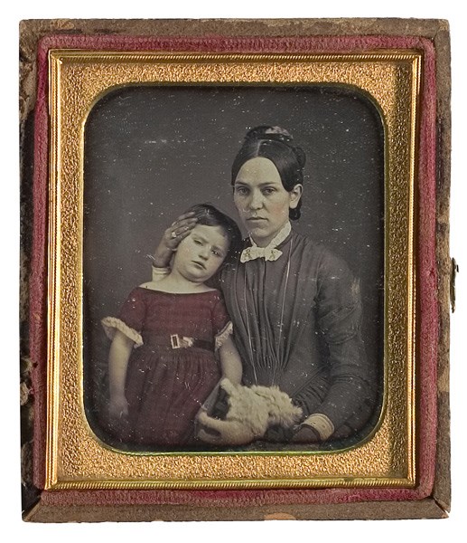 A black and white image of a seated woman and little girl.