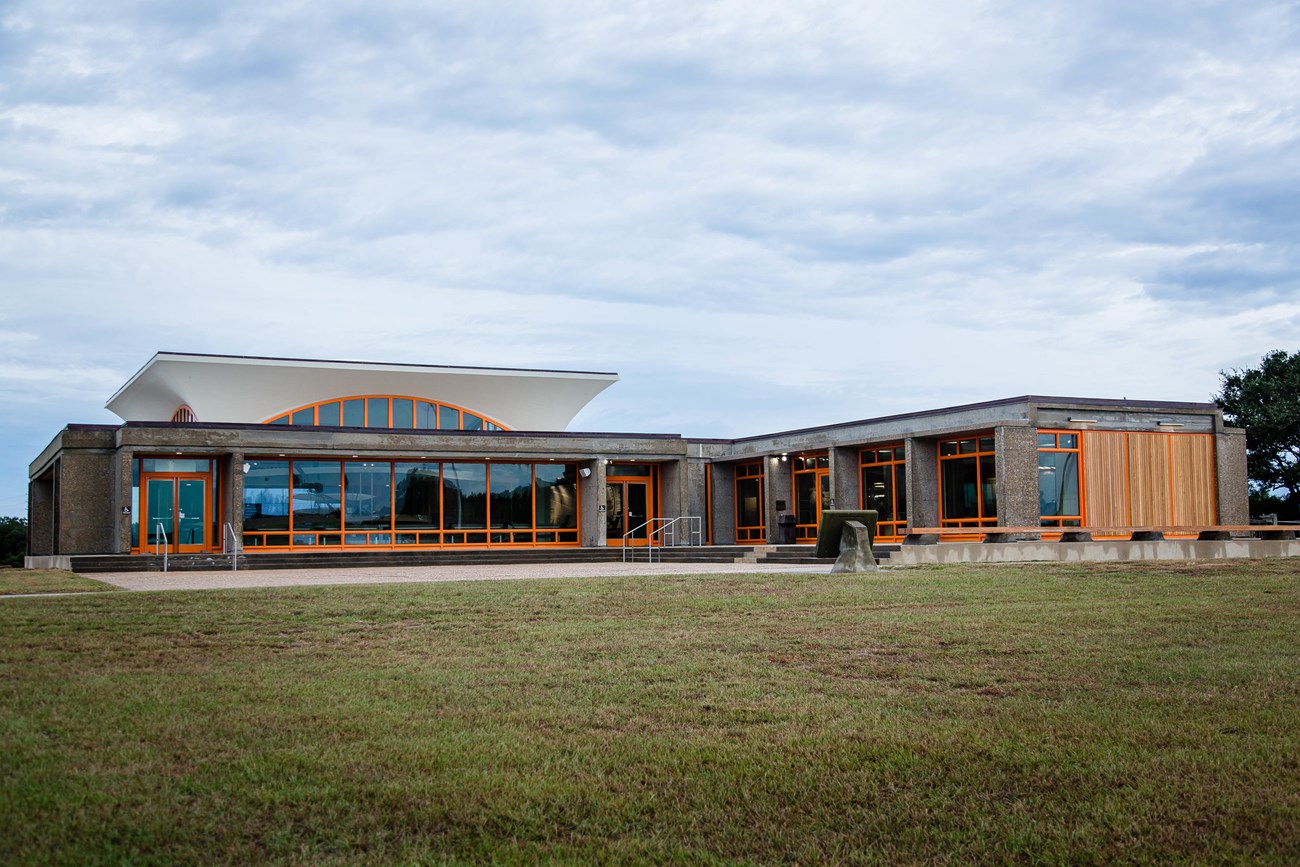 Visitor center with large glass windows lined with orange paint