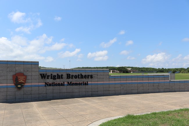 Concrete entrance gate with "Wright Brothers National Memorial" written by the Park Service arrowhead logo