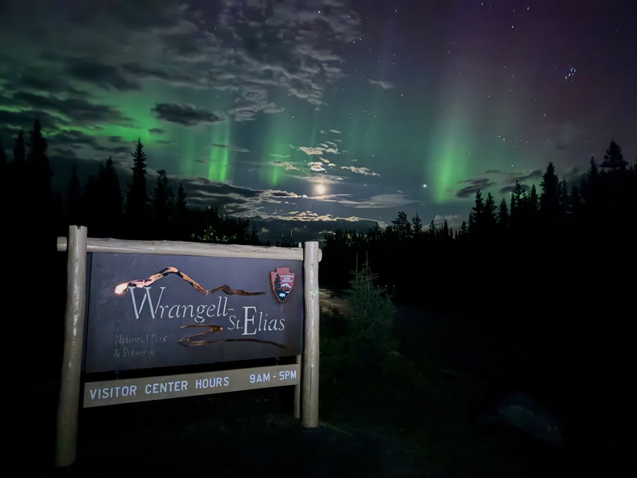 Northern Lights over the HQ entrance sign with a full moon