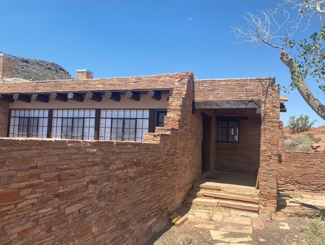 The front entryway of a late 1930s red sandstone house in the Pueblo Revival style.