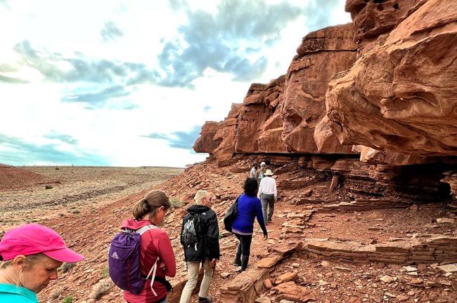 Hikers walk past the footprints of Ancestral Puebloan rooms during a ranger-led hike to the Crack in the Rock pueblo in 2022.