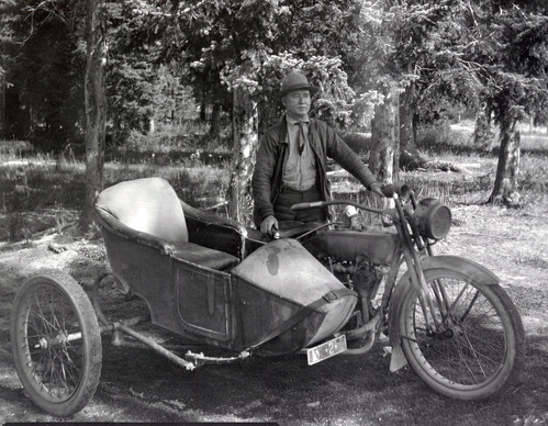 Image of a man standing next to a motorcycle and side car.