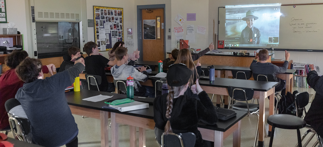 Students raise their hands in a classroom.