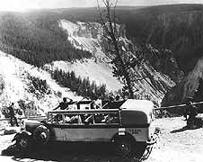 (YELL 96222) Tourists at the Grand Canyon of the Yellowstone near Artist Point in YPT Co. bus # 352, the same 1931 National Park Bus in the museum collection. Note the canvas top rolled back to allow the visitors an unobstructed view.