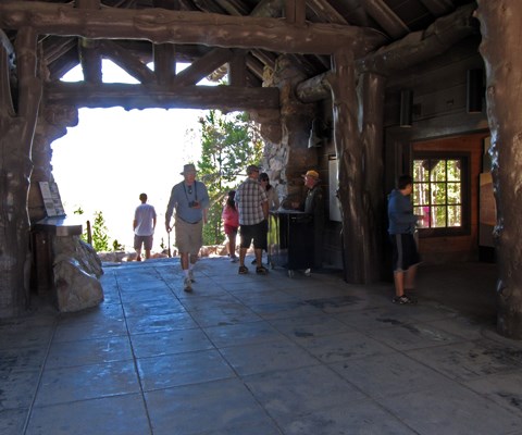People walk through a breezeway between a stone building's wings