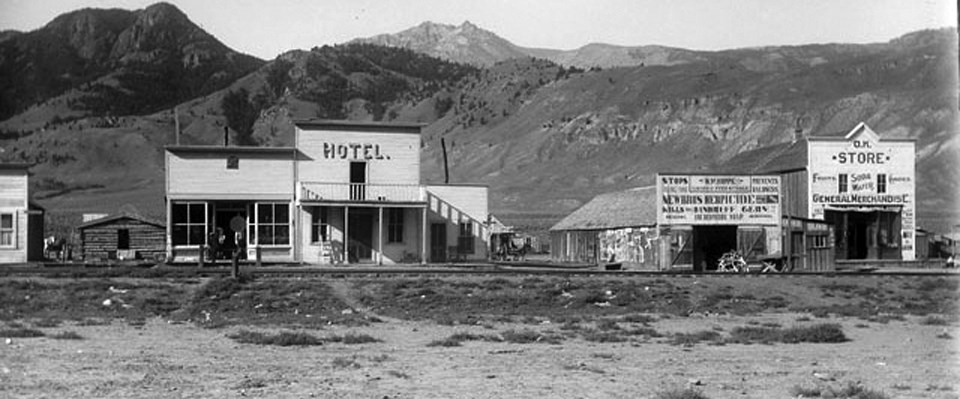 A historic photo of western town buildings in front of mountains