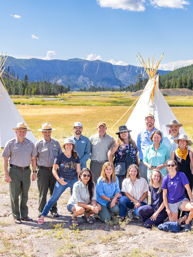 a large group of people standing in front of a large white teepee