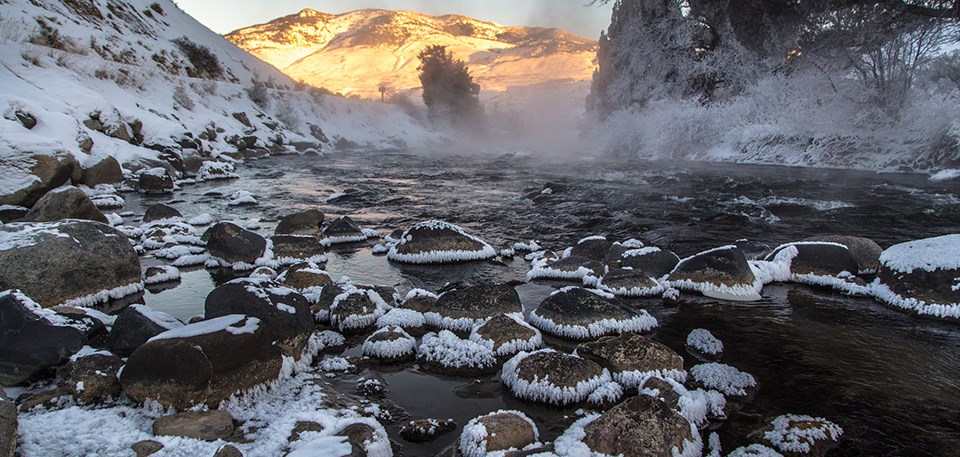 Sunrise peaks over the horizon of a frosty stream.