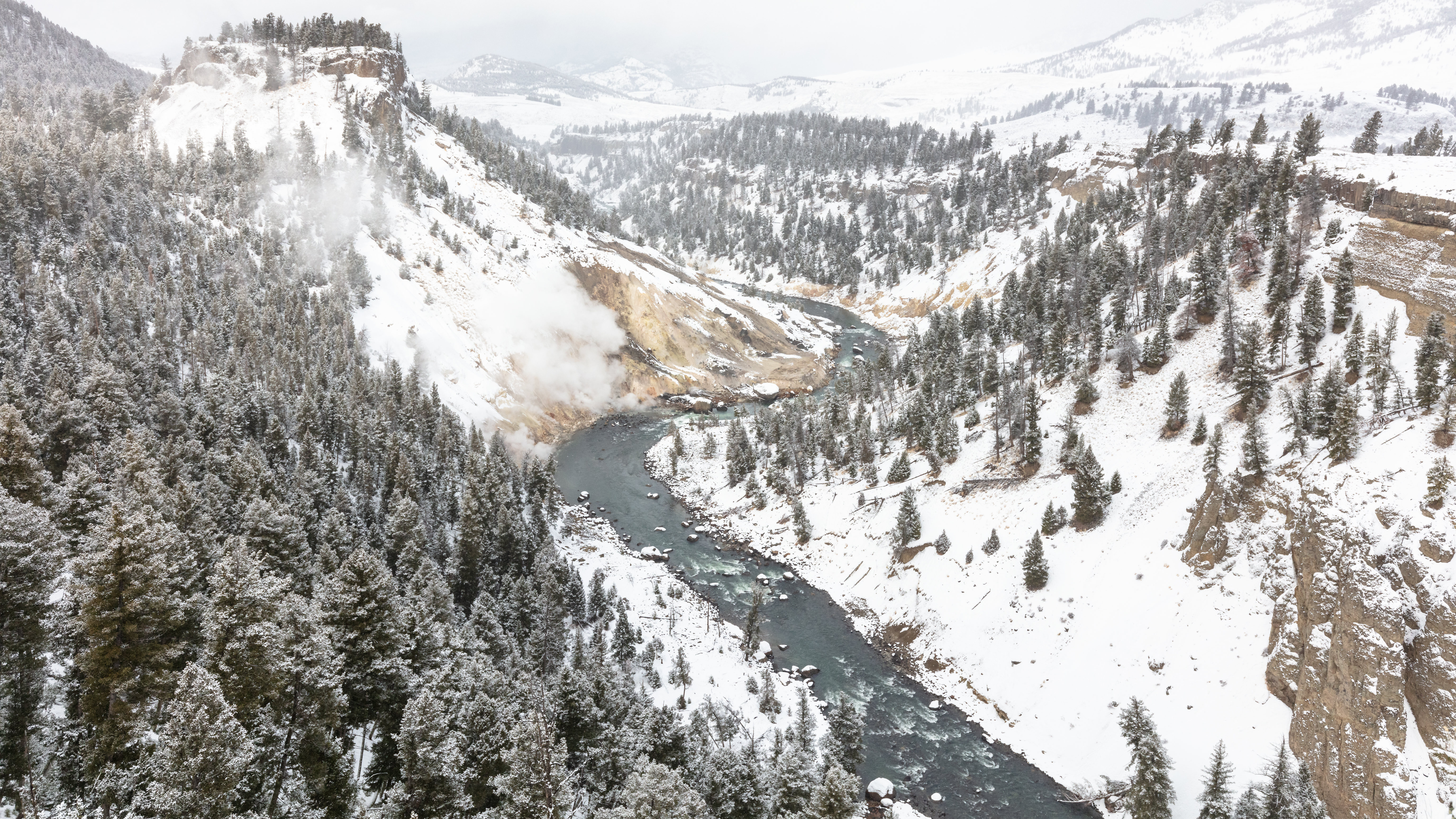 Snow covers a canyon above a large river