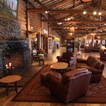 leather chairs and couch are located near a fireplace, in a large log-cabin style lodge room