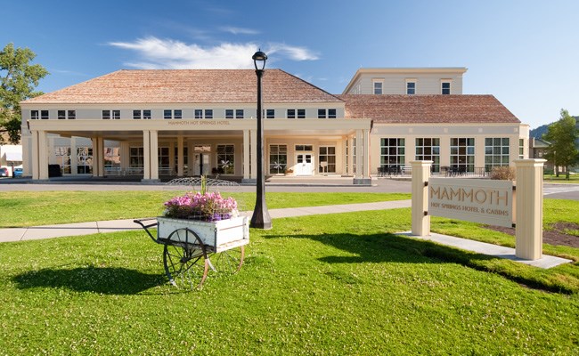 A hotel with a large carport and a flower cart out front.