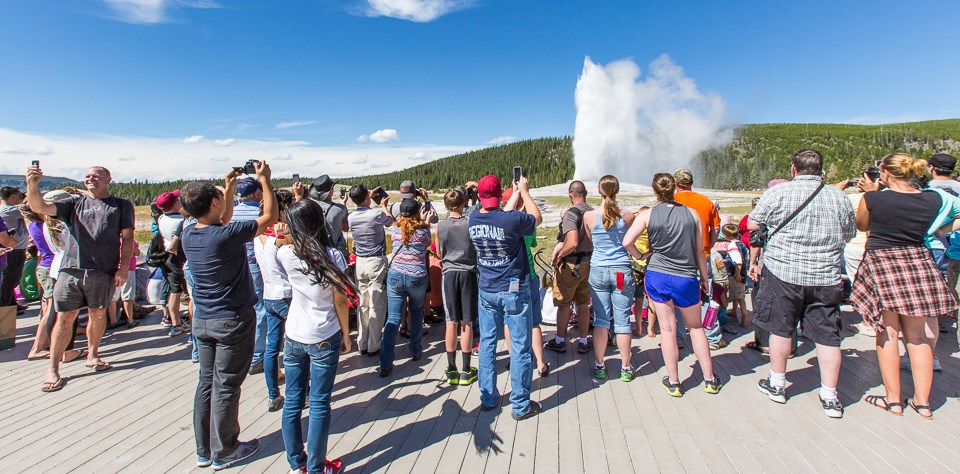 People using cell phones during an eruption of Old Faithful