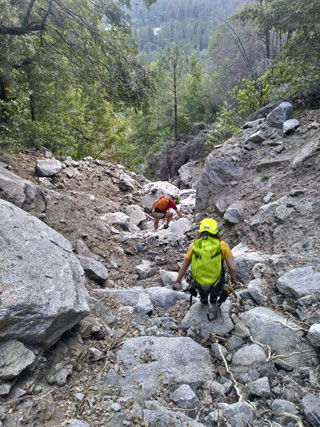 Rescuer and hiker descending steep canyon