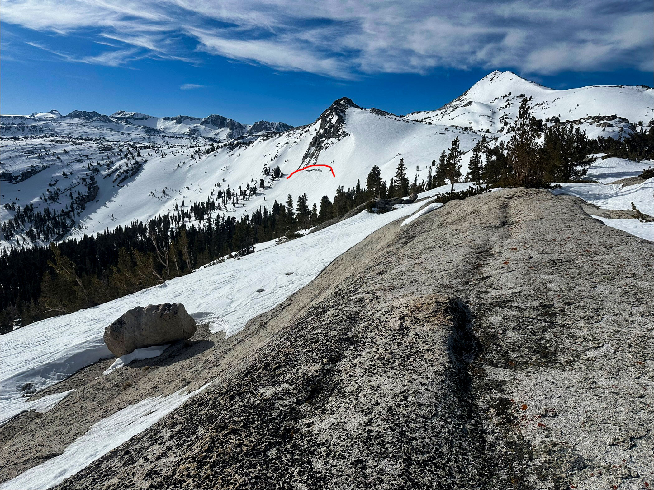 View from a distance of a snowy slope, with a avalanche glide crack highlighted 