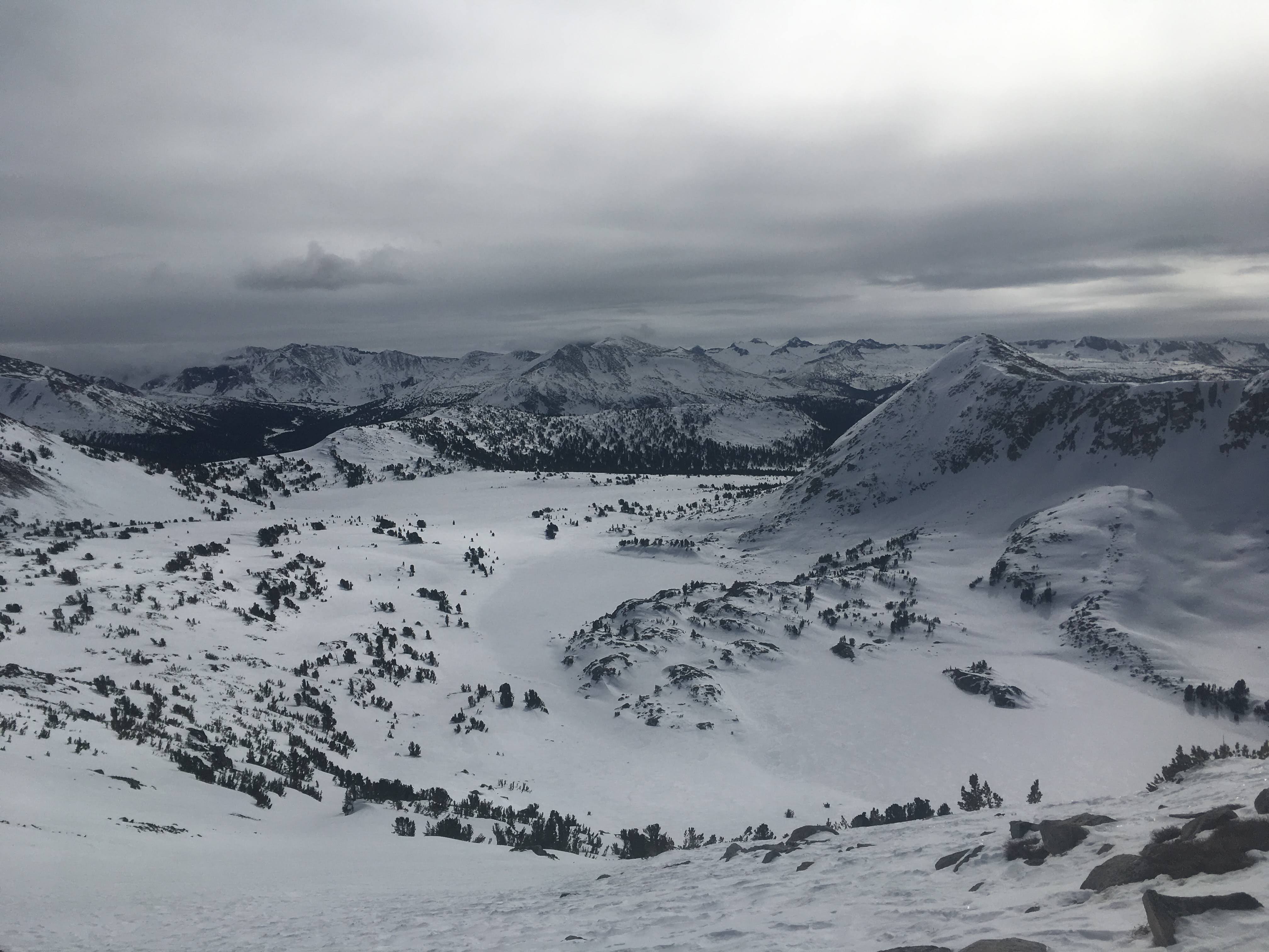 A wide view of a snowy basin under the cloud-covered sky