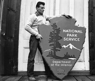 Man standing next to National Park Service arrowhead