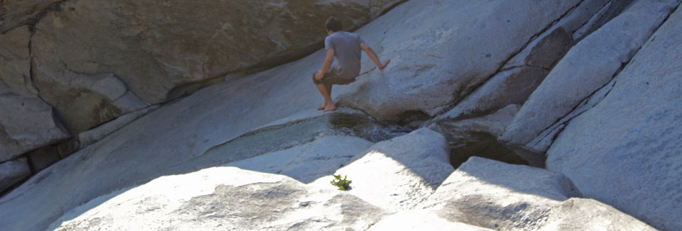 Man walking alongside a small creak on slick granite
