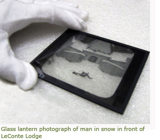 Image of glass lantern slide and museum technician's gloved hand holding it.