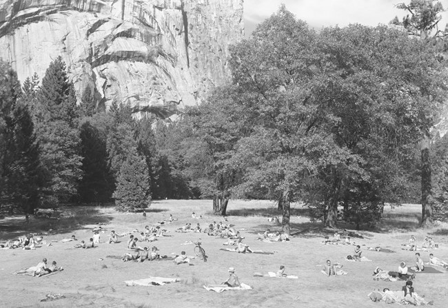 Sunbathers relax in a meadow with Royal Arches in the background