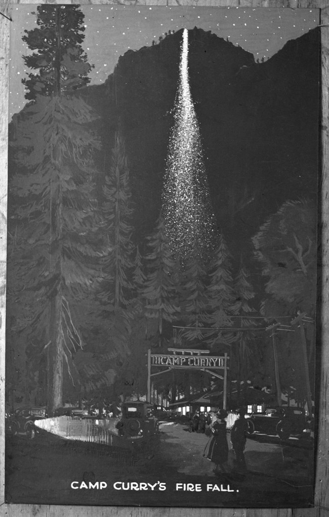 Black and white photo of cliff face with a seemingly white fall behind a sign that reads Camp Curry