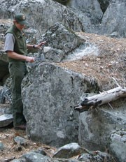 Ranger holds tool above rock fall rubble