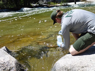 Person taking a water sample from above Nevada Fall in June 2017
