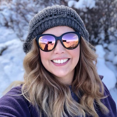 Headshot of a woman with blone hair wearing a beanie and sunglasses