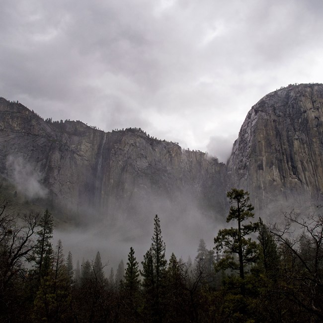 Ribbon Fall with light flow and clouds beneath it; El Capitan to the right