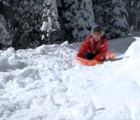 Child sledding down a snowy hill.