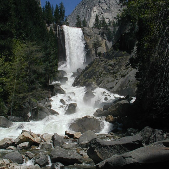 Looking upstream toward Vernal Fall as the Merced River crashes among boulders in the foreground